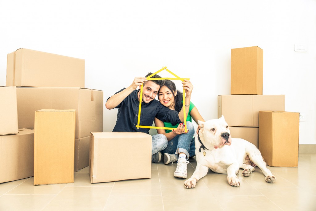 Happy couple with dog moving to a new home - Cheerful family starting a new life - Multi ethnic couple of lovers buy new apartment